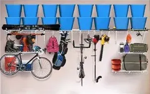 Wall-mounted garage storage with blue bins, hanging tools, bikes, and household items on shelves and hooks