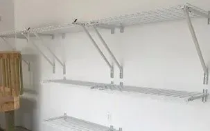 White wire shelving units mounted on a wall in a closet or storage room