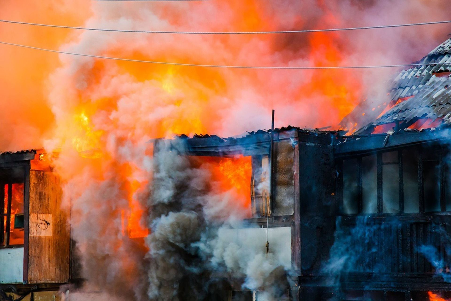 House engulfed in flames with thick smoke billowing from the roof and windows