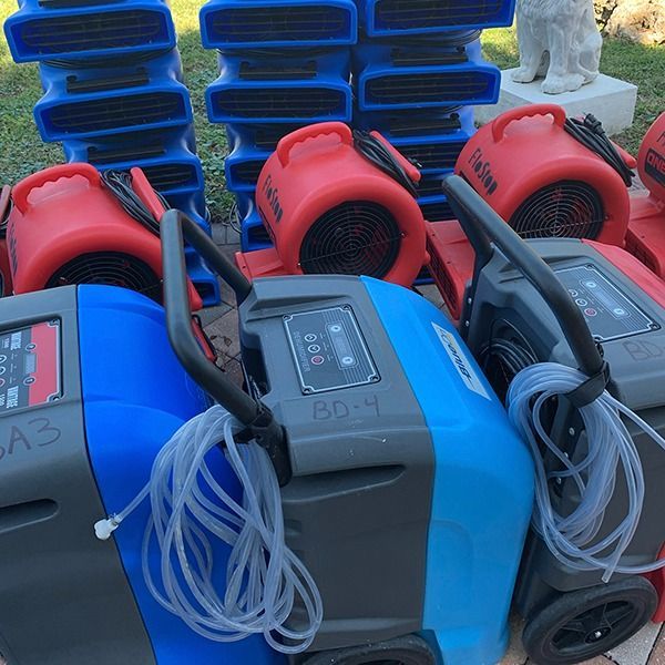 Red and blue portable blowers with coiled cords stacked outdoors on a cart