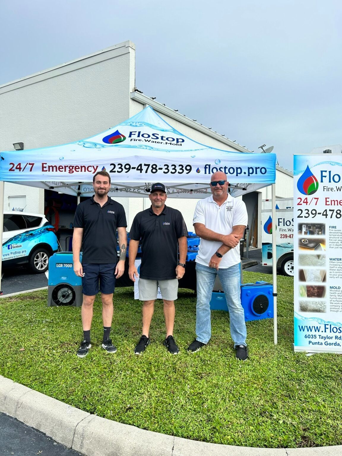 Three men standing in front of a pest control service truck and sign on a grassy roadside.