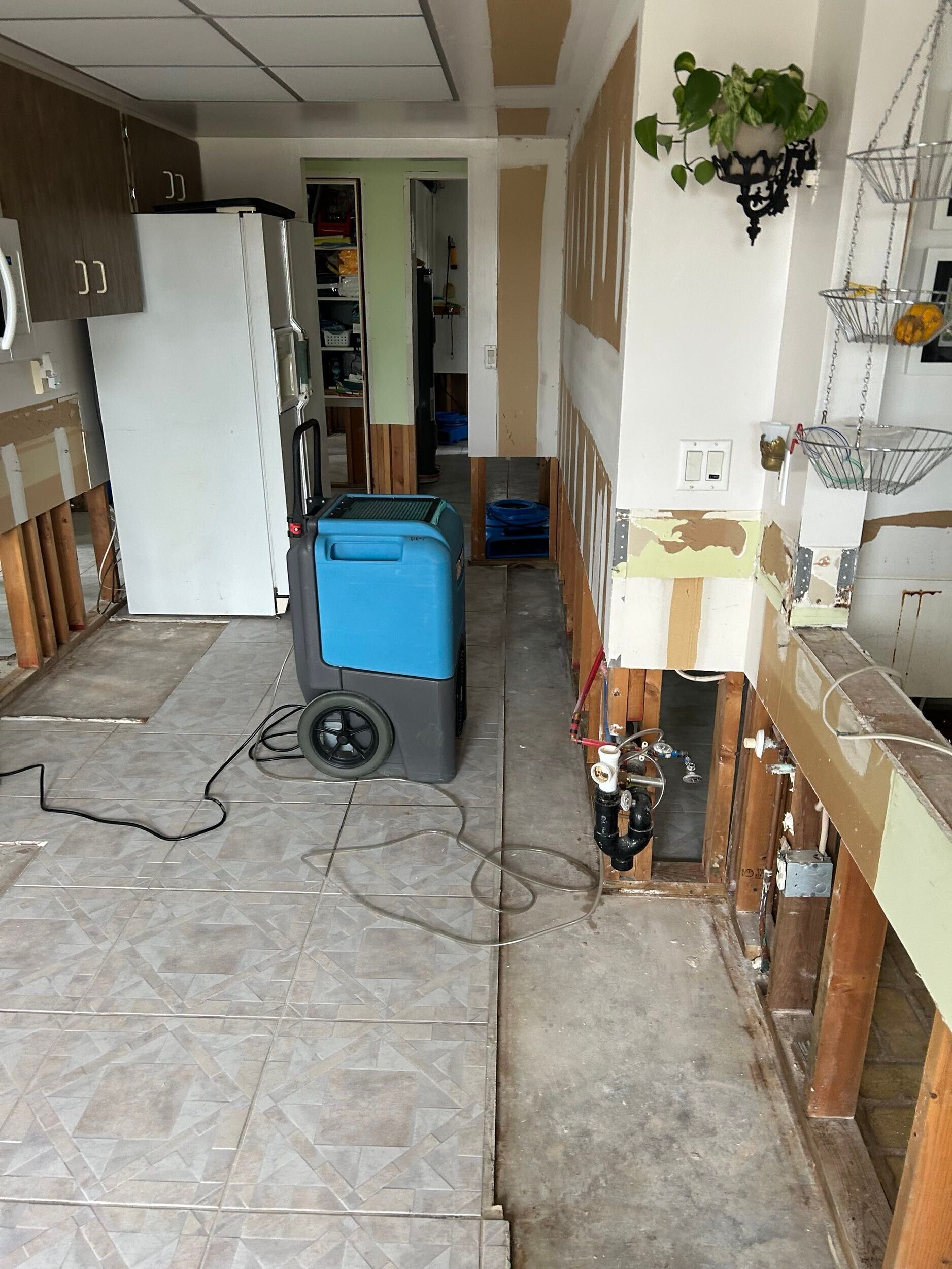 Indoor hallway with a blue utility machine, cords on the floor, and a partially renovated wall.