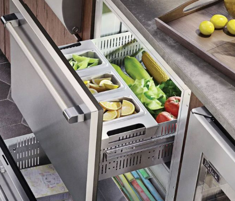 Open kitchen drawer organizer with fresh vegetables and produce stored in compartments.