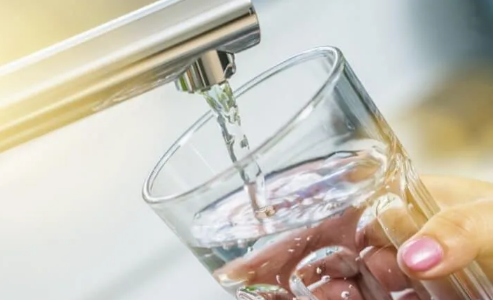 Water pouring from a faucet into a clear glass held under it