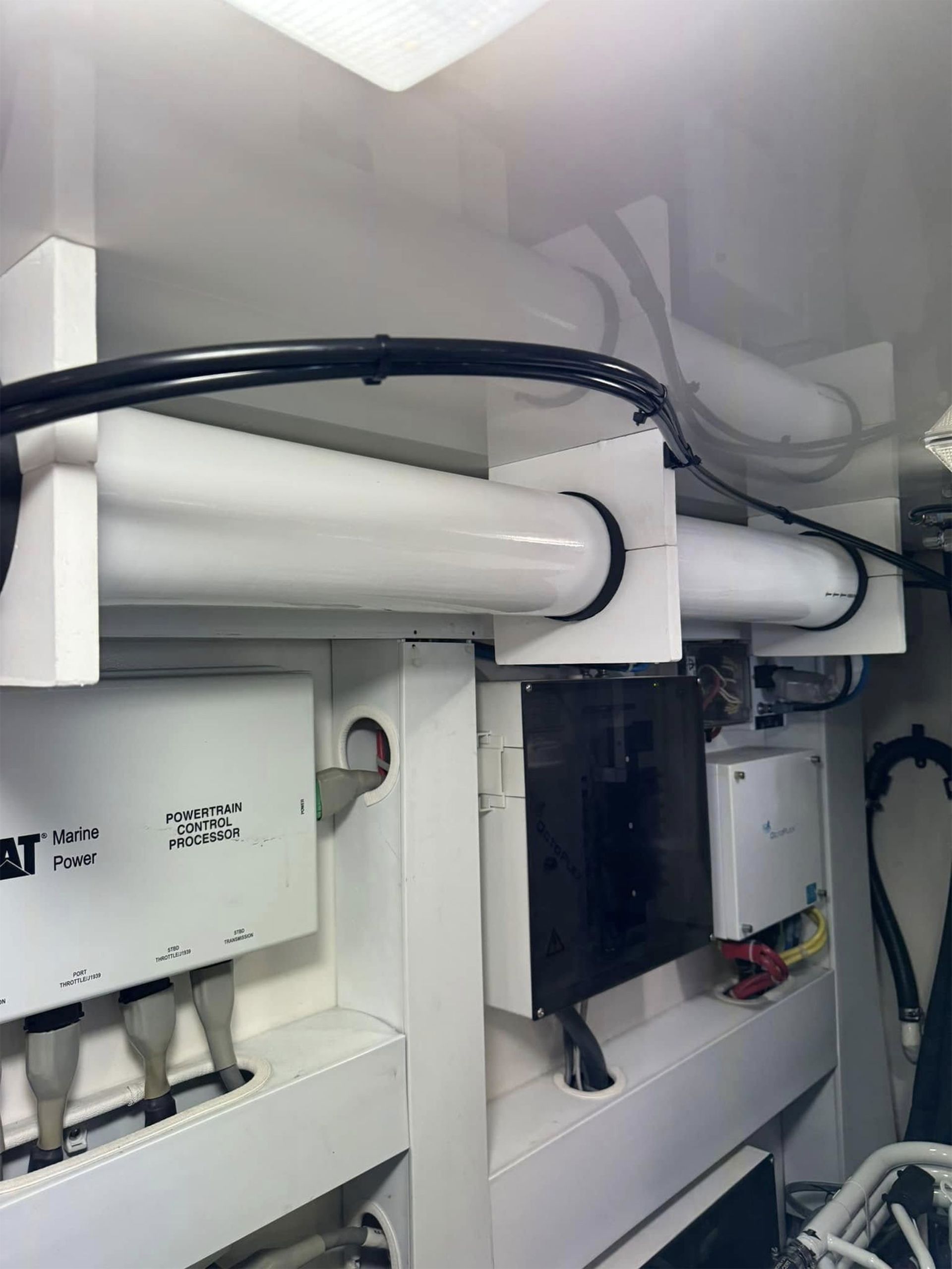 White pipes and black cables inside a mechanical cabinet or utility room