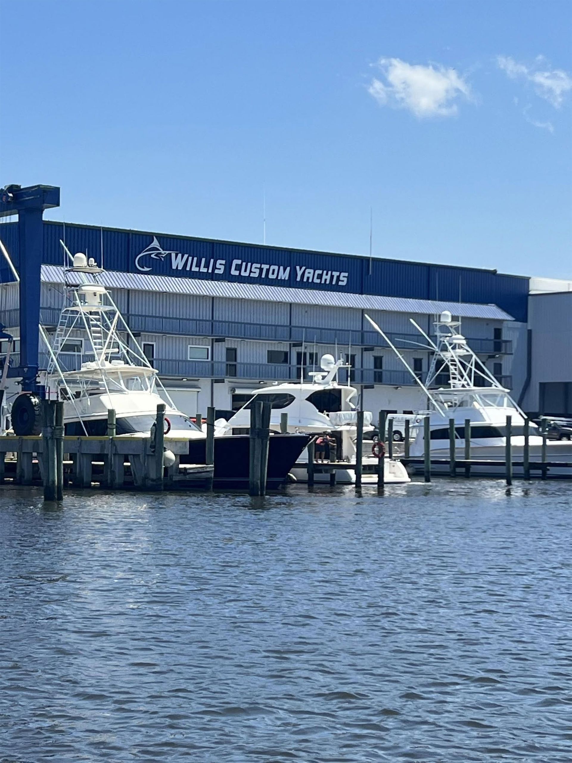 Boats docked by the blue Thalys County Theater building on a sunny waterfront.