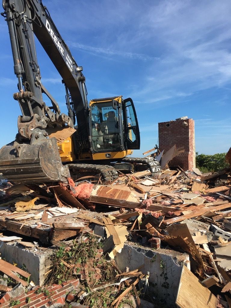 demolition excavator tearing down a building on a sunny day
