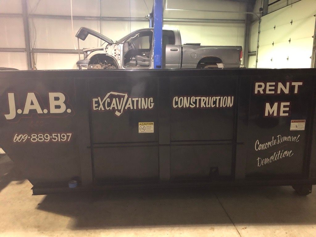 black dumpster in a garage; a truck is visible in the background