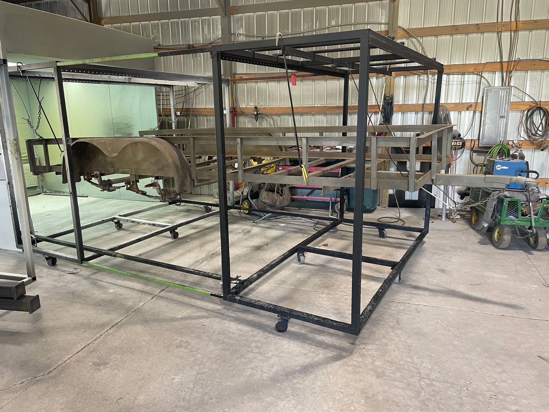 Black metal frame around an old truck bed, possibly for a project, in a workshop.