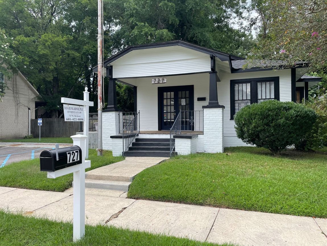 A white office building with a front porch and a sign for Dana Bumgardner, P.L.L.C., Attorney at Law 