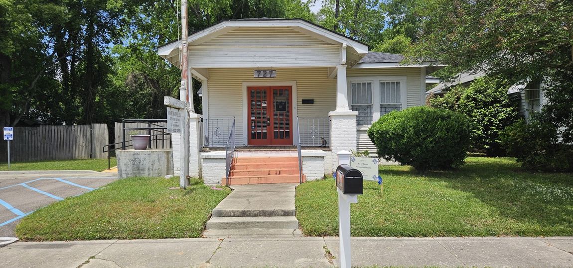 A white office building with a front porch and a sign for Dana Bumgardner, P.L.L.C., Attorney at Law 