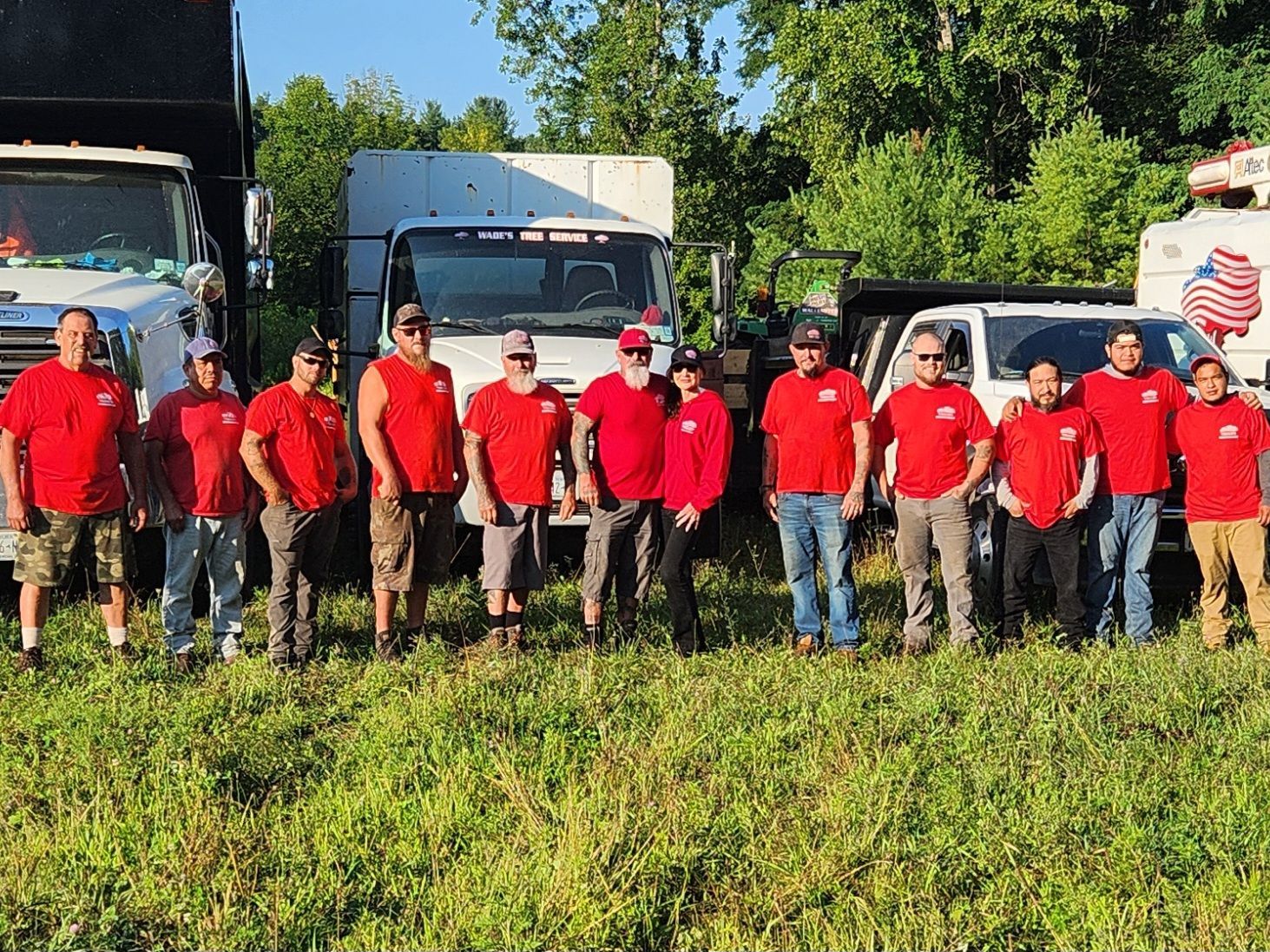 Group of people in red shirts posing in front of trucks outdoors.
