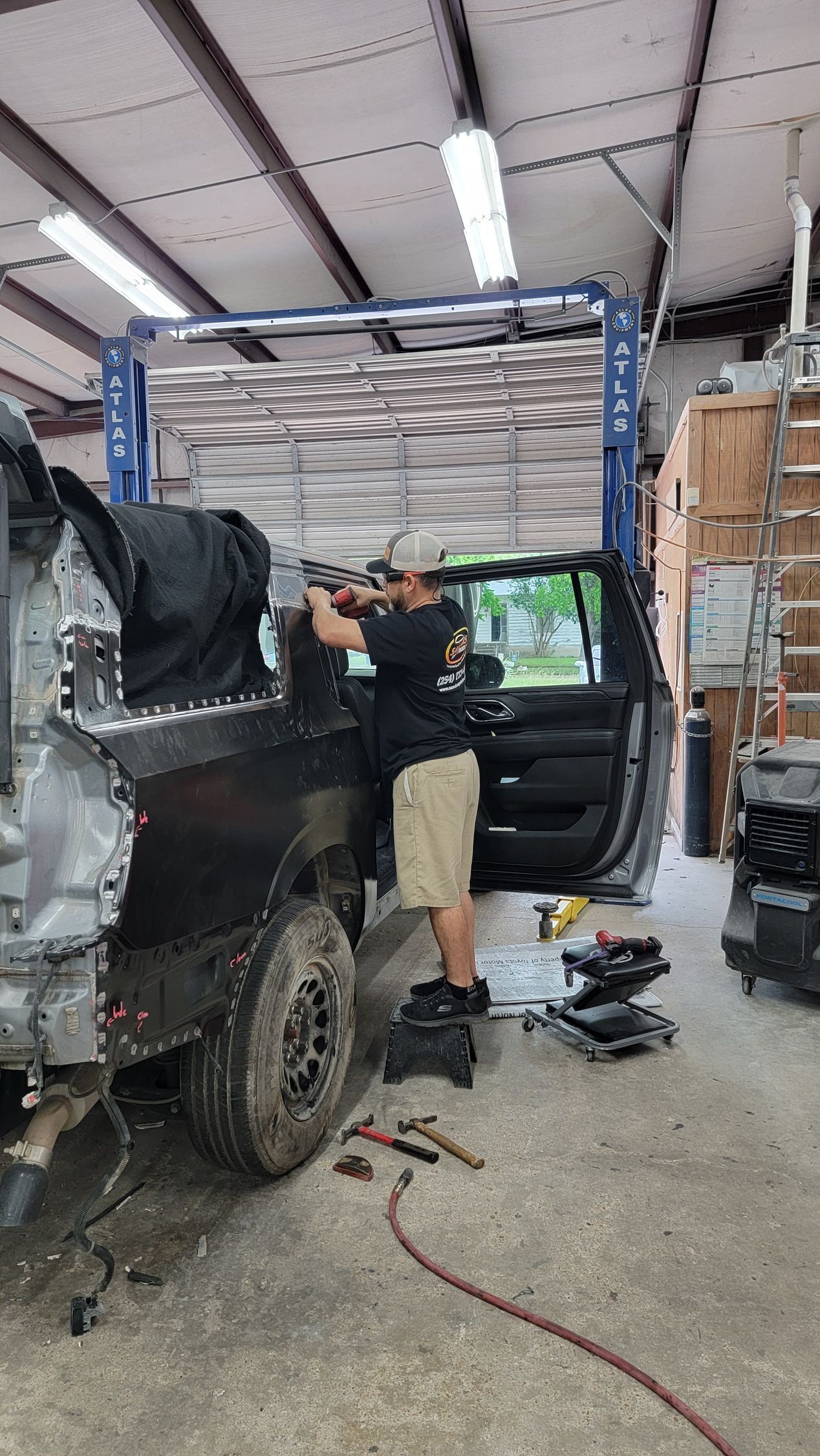 Mechanic working on a lifted black truck inside an auto repair shop