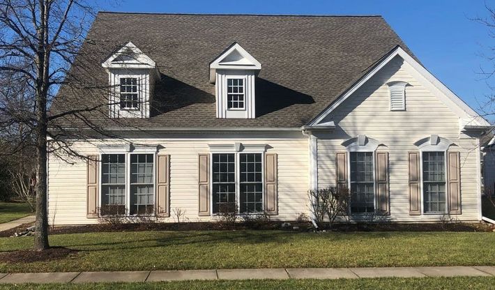 A white house with a brown roof and shutters