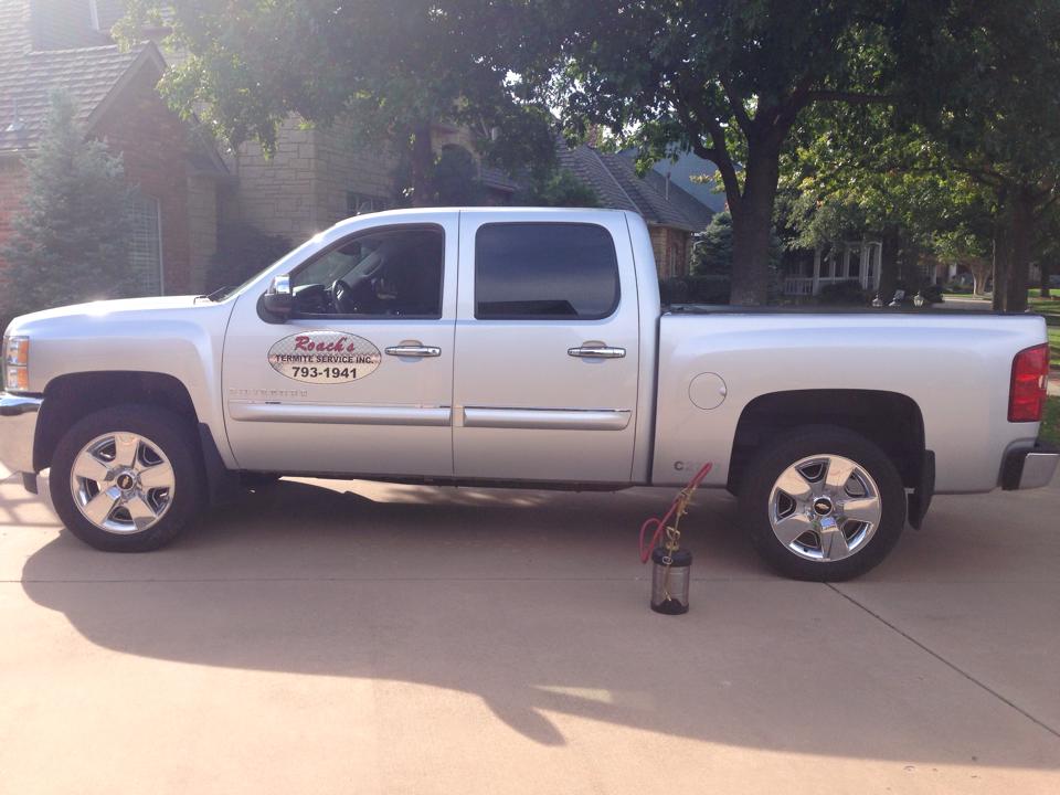 White pickup truck with 'Roach's Termite Service' logo and contact number parked in a driveway, ready for termite inspection and treatment