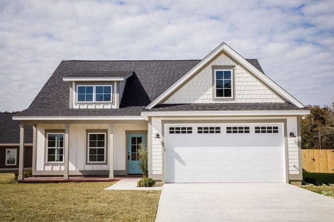 A one-story suburban home with a white exterior, gray shingled roof, a light blue front door, and a two-car garage.