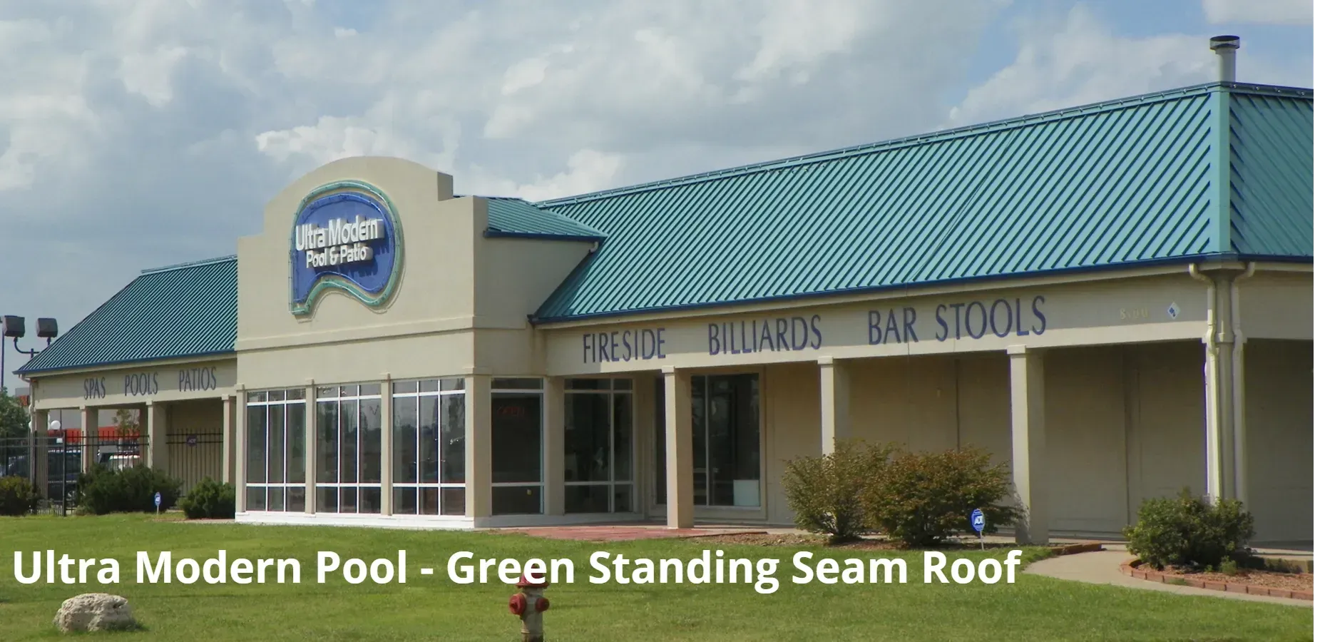 A commercial building with tan walls and a green standing seam metal roof, featuring a sign reading 