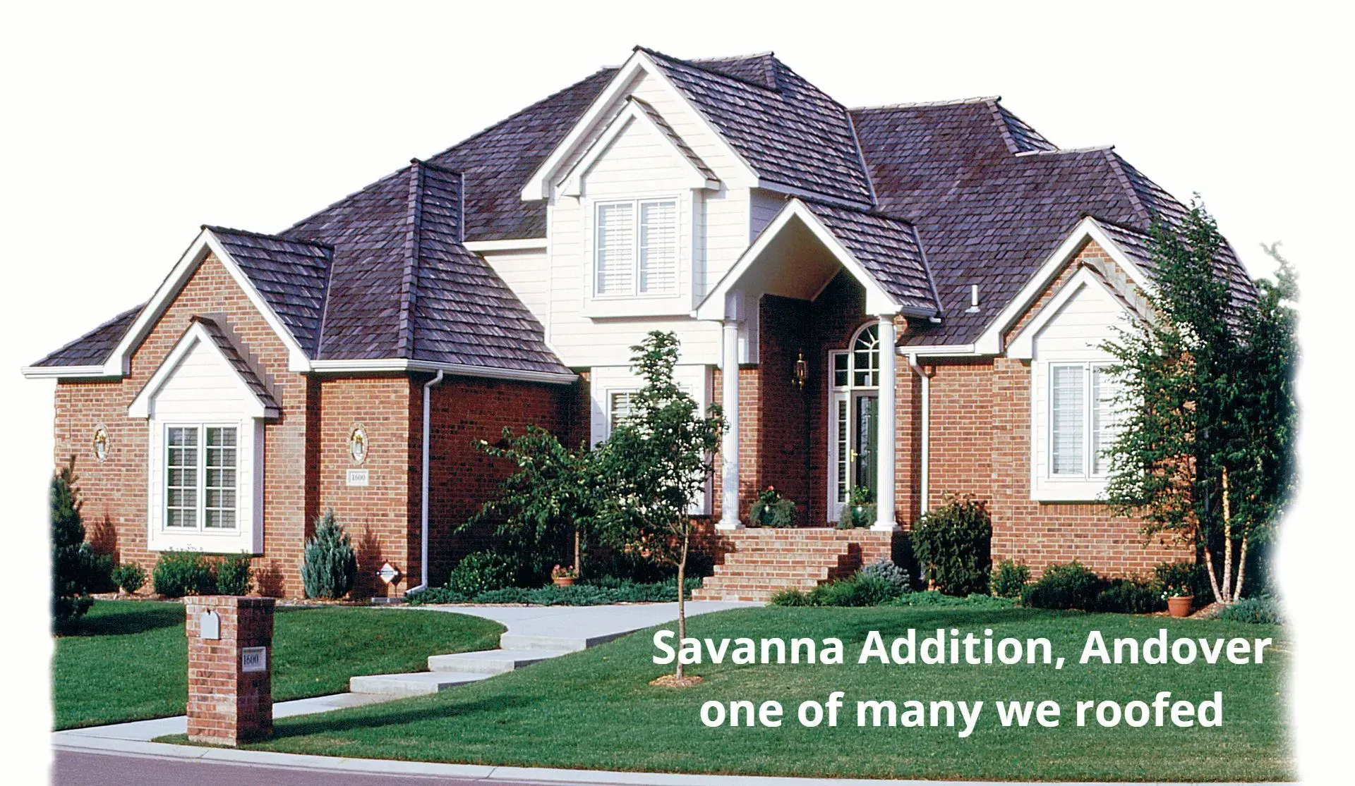 A brick-and-siding house in Savanna Addition, Andover, featuring a dark shingle roof, surrounded by lawn and landscaping.