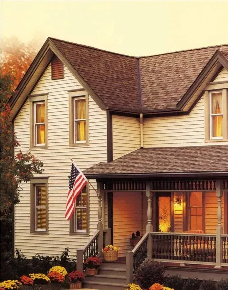 A two-story house with cream siding, dark trim, a covered porch, and an American flag flying by the steps.