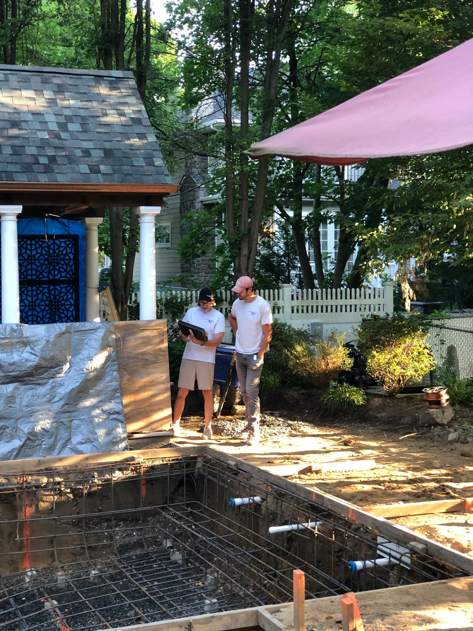 Two men are standing next to a swimming pool under construction.