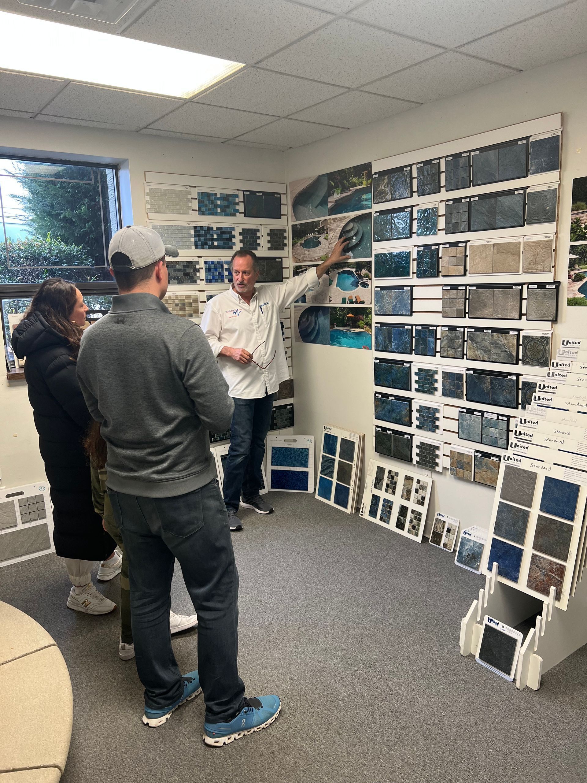 A group of people are standing in a room looking at tiles.
