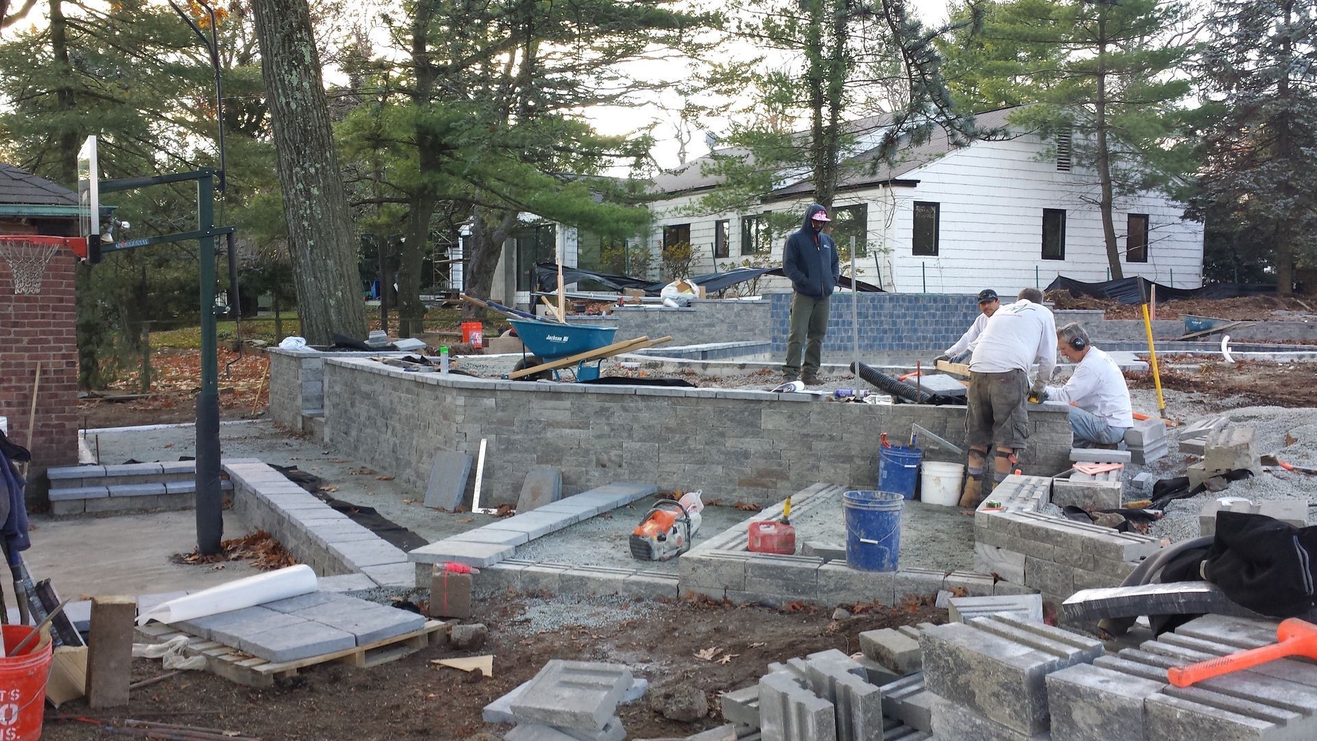 A group of men are working on a construction site in front of a house.