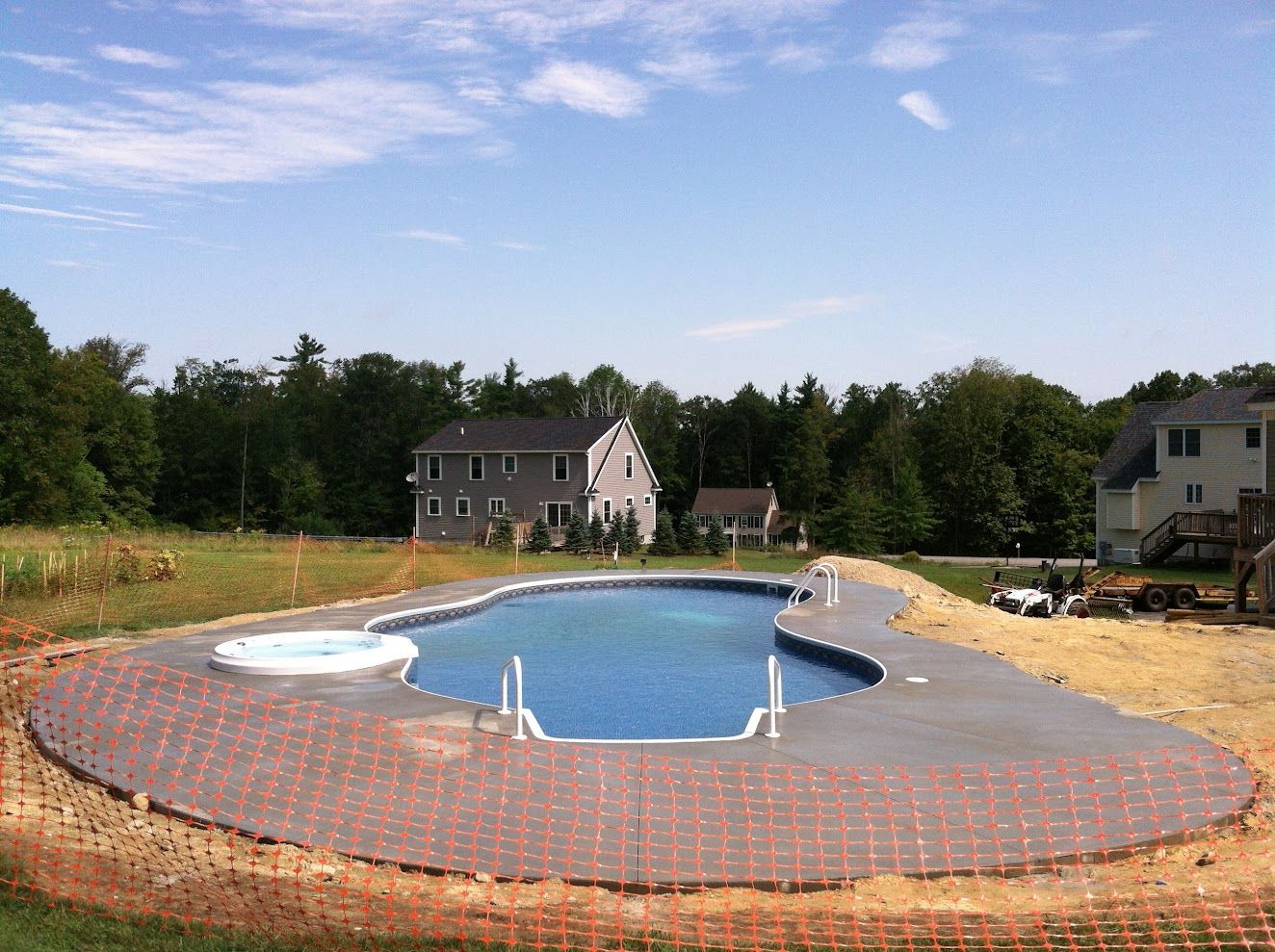 A large swimming pool is being built in the backyard of a house.