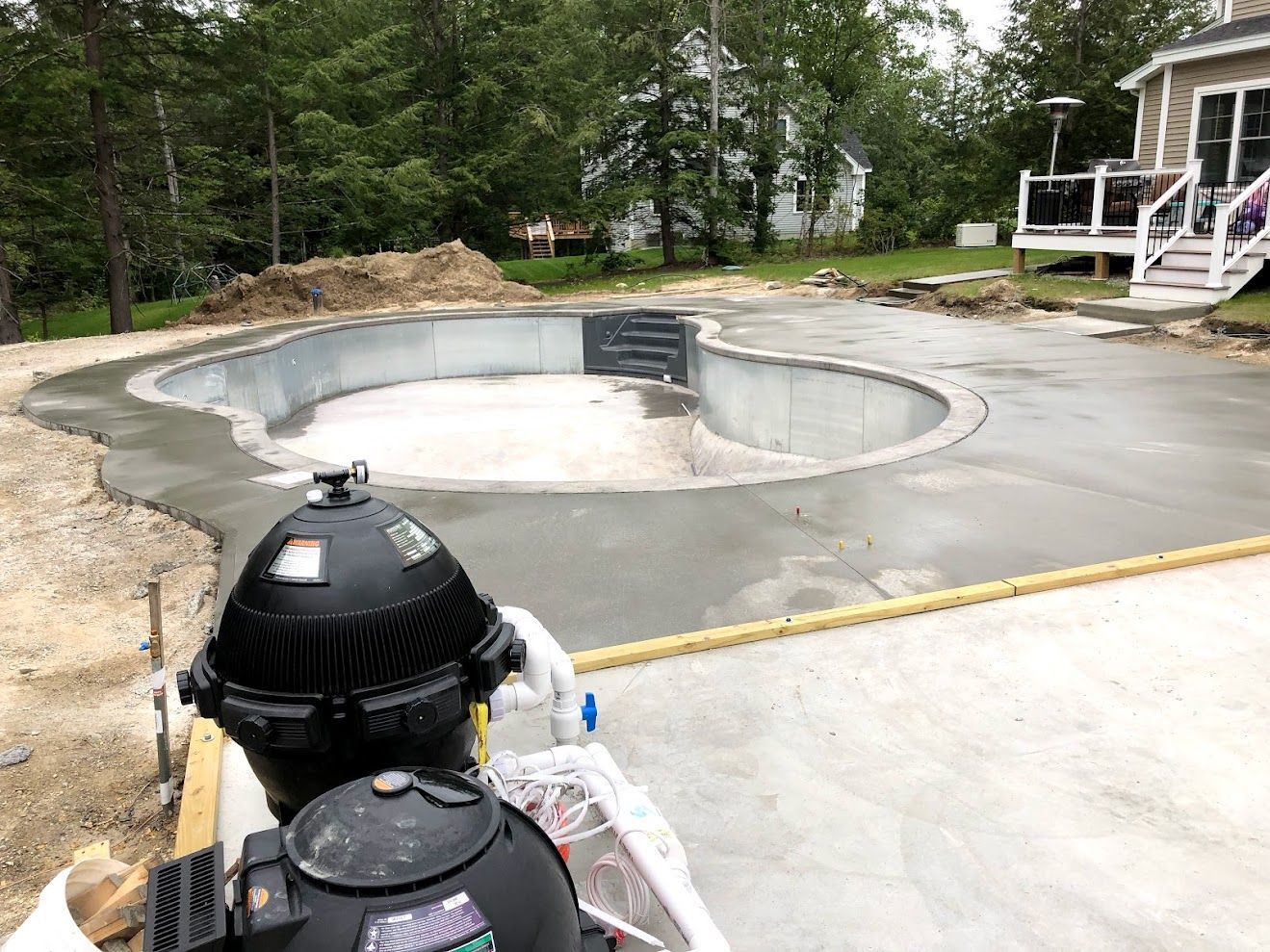 A large swimming pool is being built in the backyard of a house.