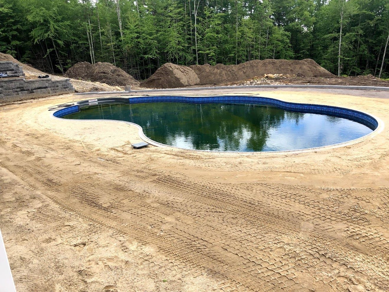 A large swimming pool is being built in the middle of a dirt field.