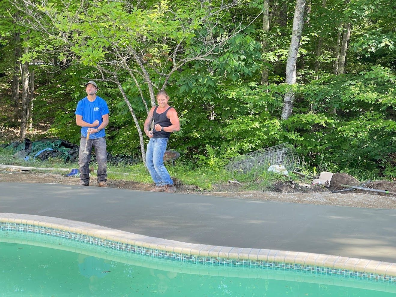 A man and a woman are standing next to a swimming pool.