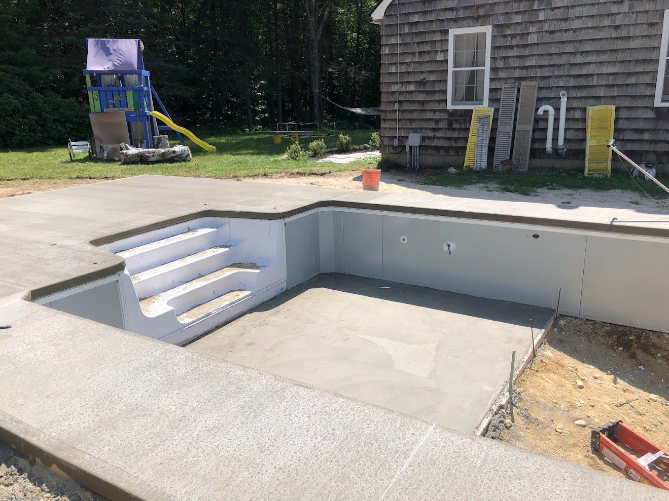 A swimming pool is being built in the backyard of a house.