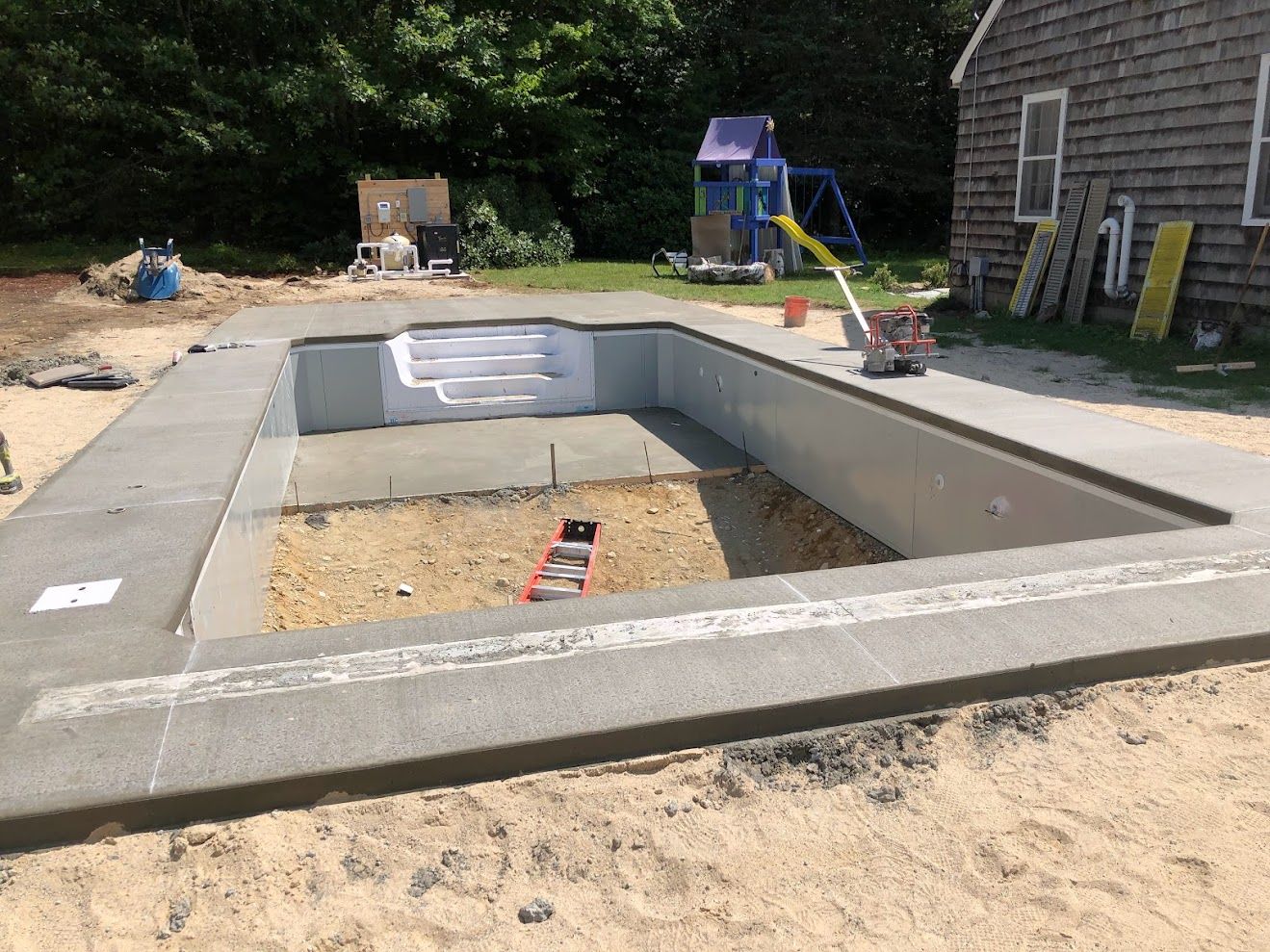 A swimming pool is being built in the backyard of a house.