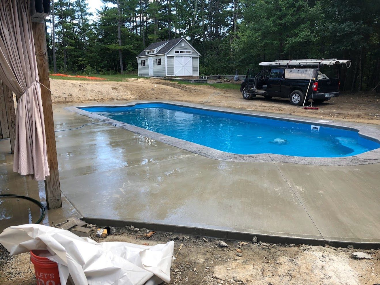 A large swimming pool is being built in the backyard of a house.