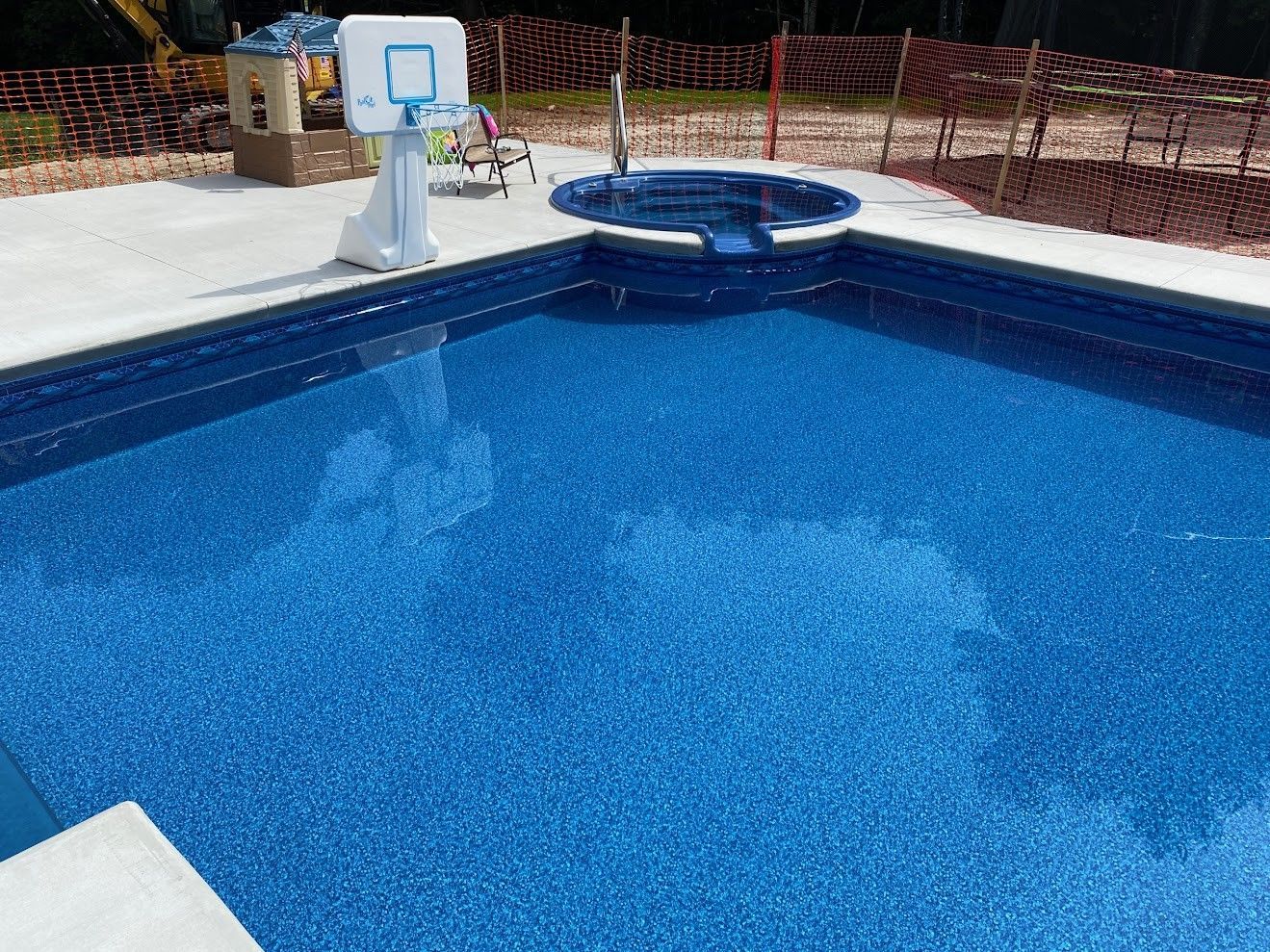 There is a basketball hoop in the middle of the pool.