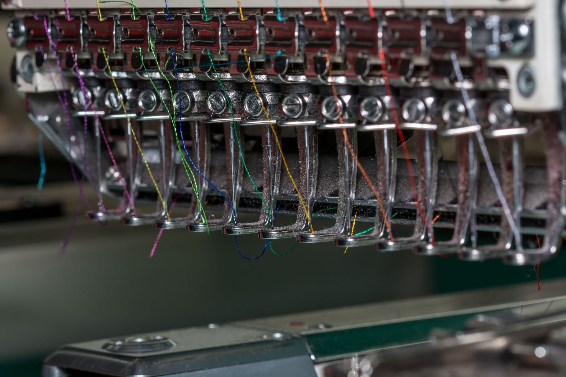 Close-up of a multi-needle embroidery machine with various colored threads.