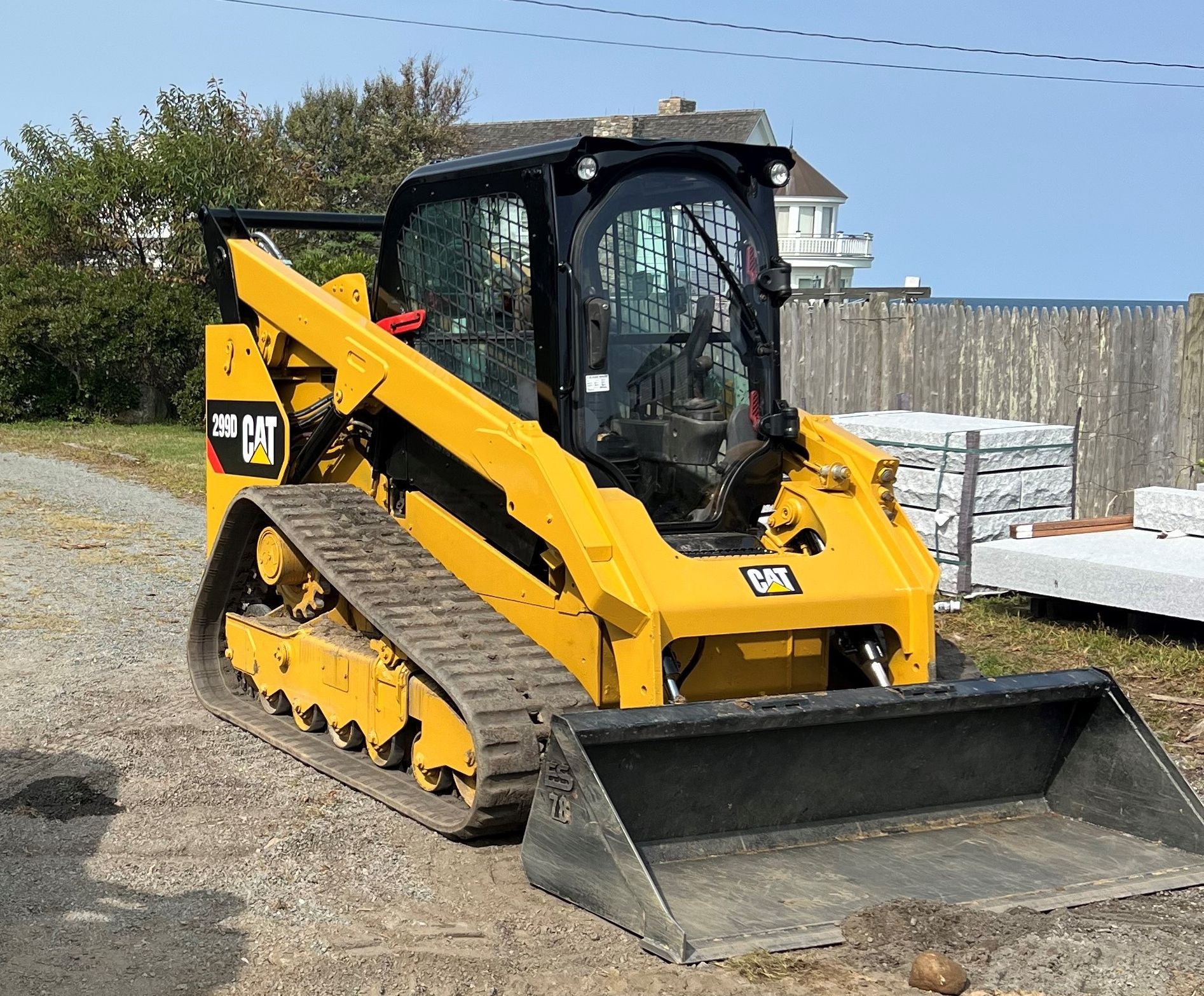 A yellow cat bulldozer is parked in a gravel lot