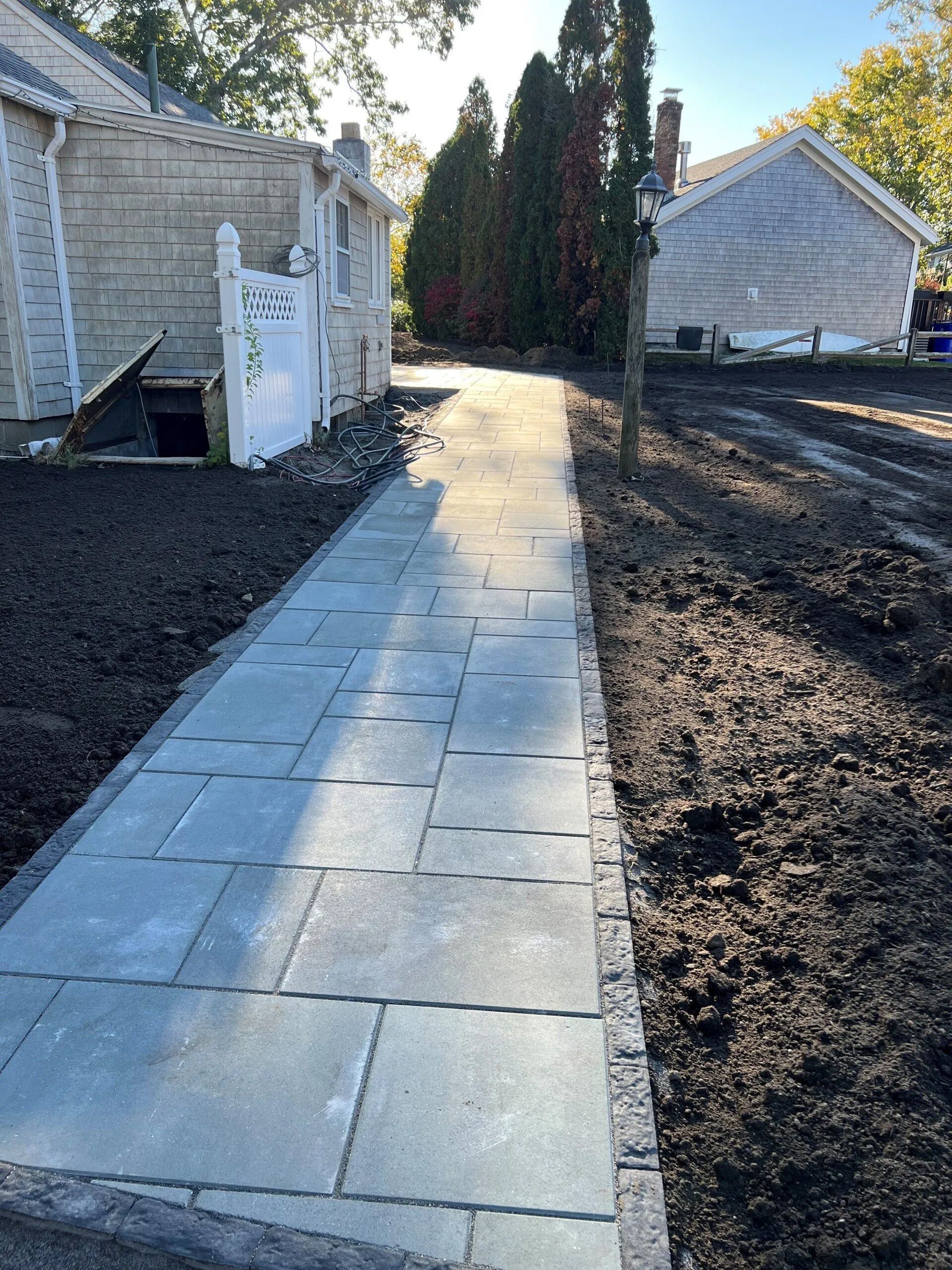A walkway leading to a house with a white gate
