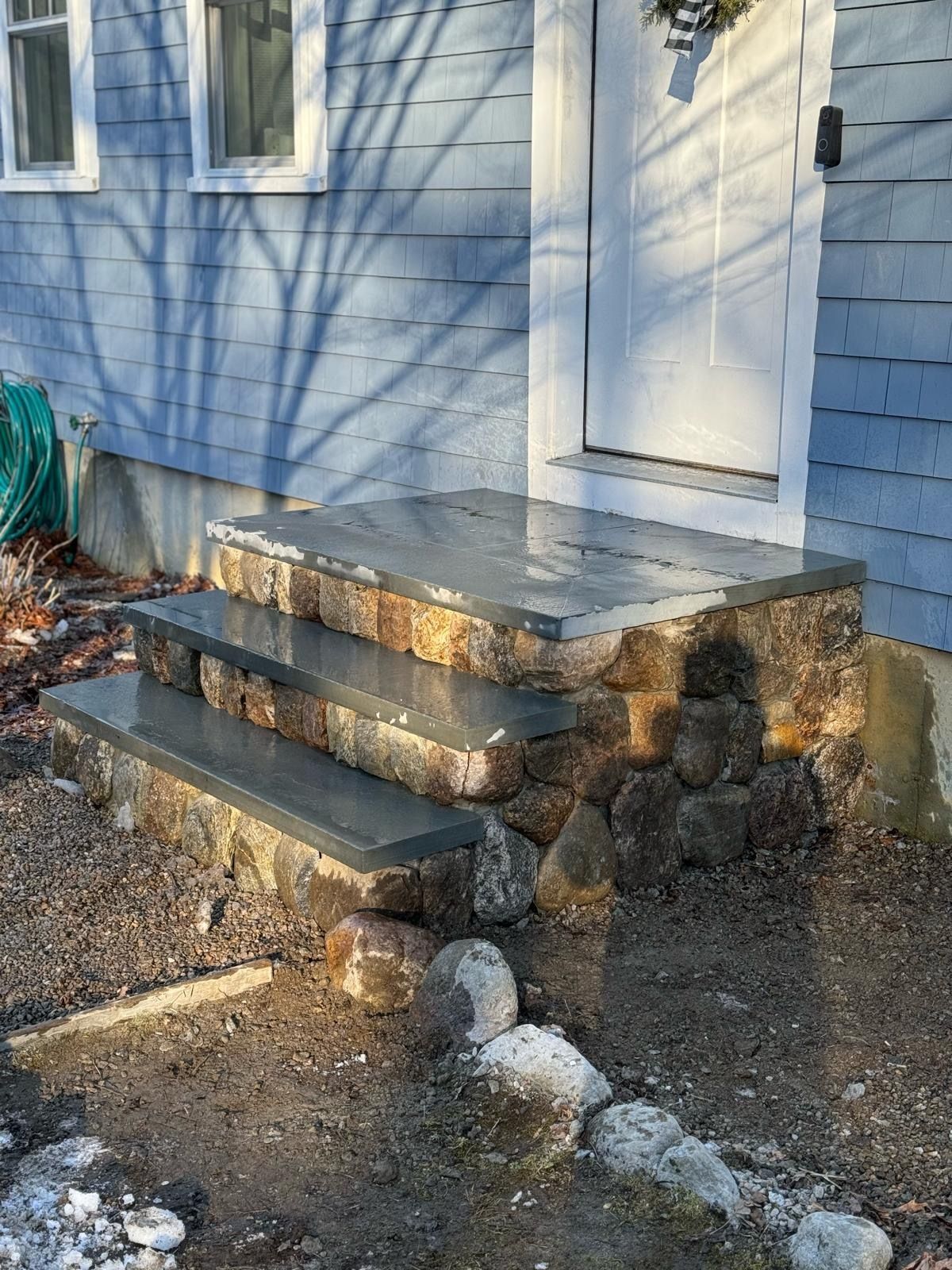 A blue house with stone steps leading up to the front door