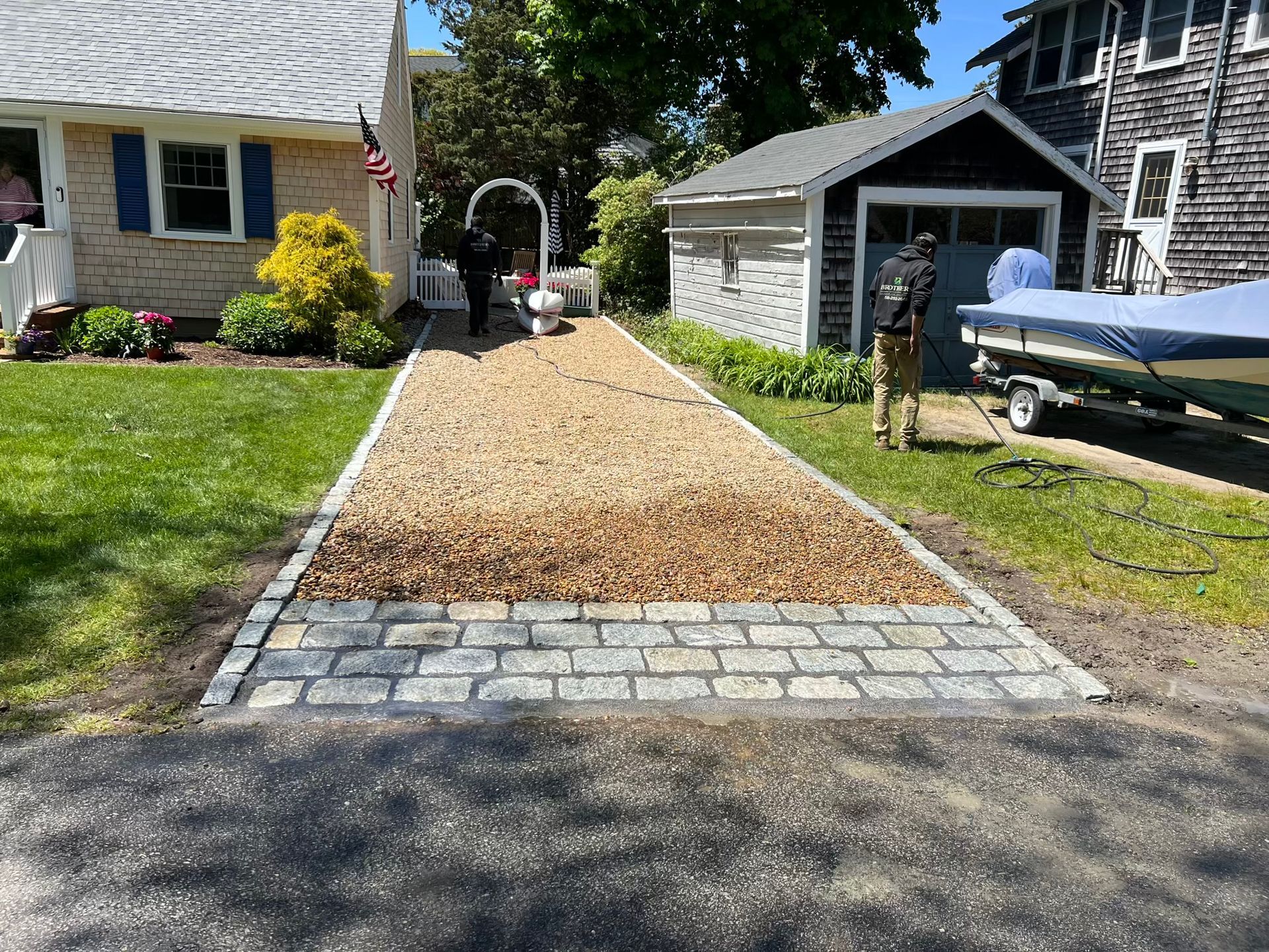A man is pushing a boat down a driveway next to a house