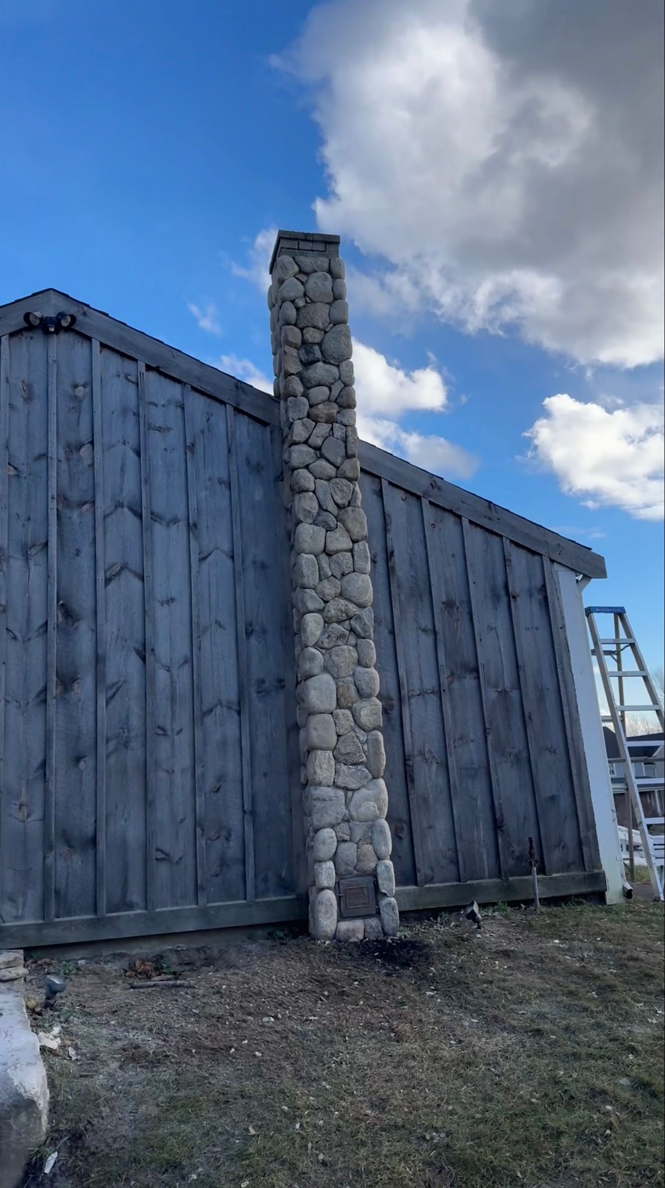A stone chimney is sitting on the side of a wooden building