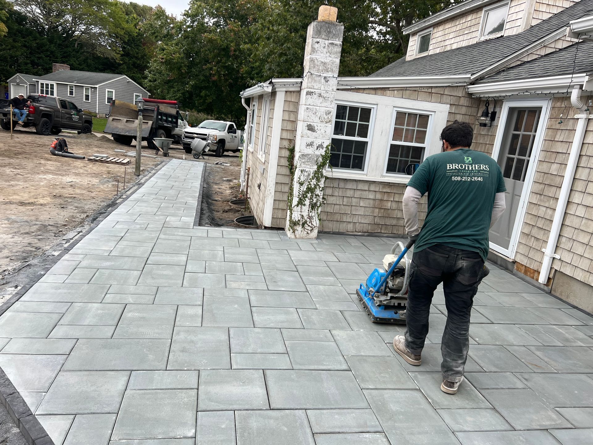 A man is working on a patio in front of a house
