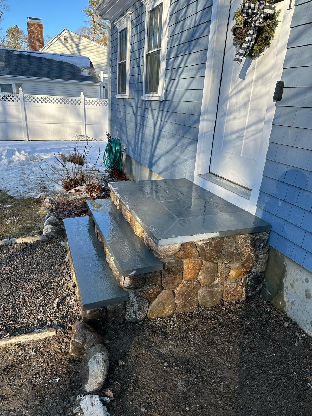 A blue house with a stone porch and steps in front of it