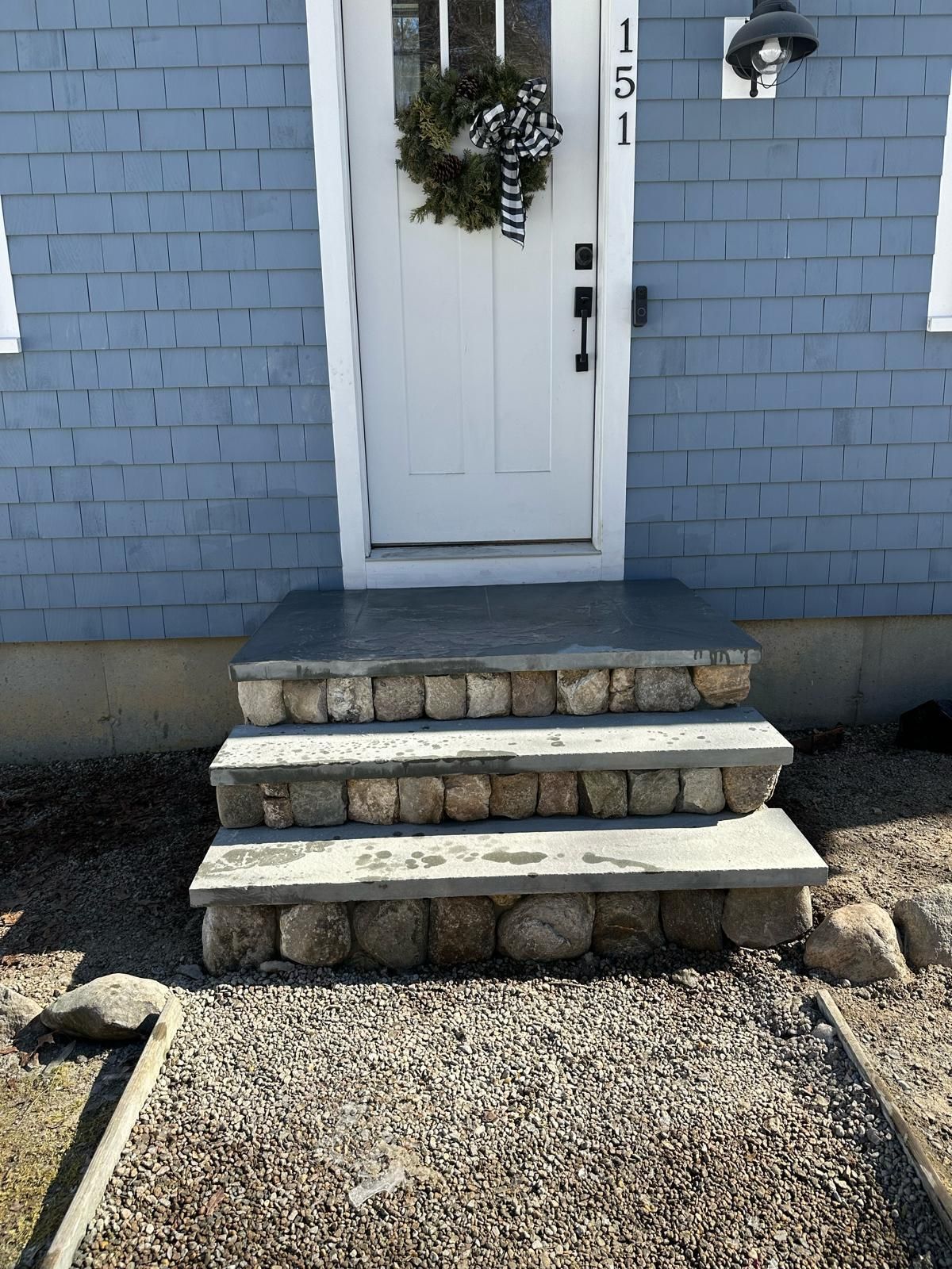 A blue brick house with a white door and stone steps