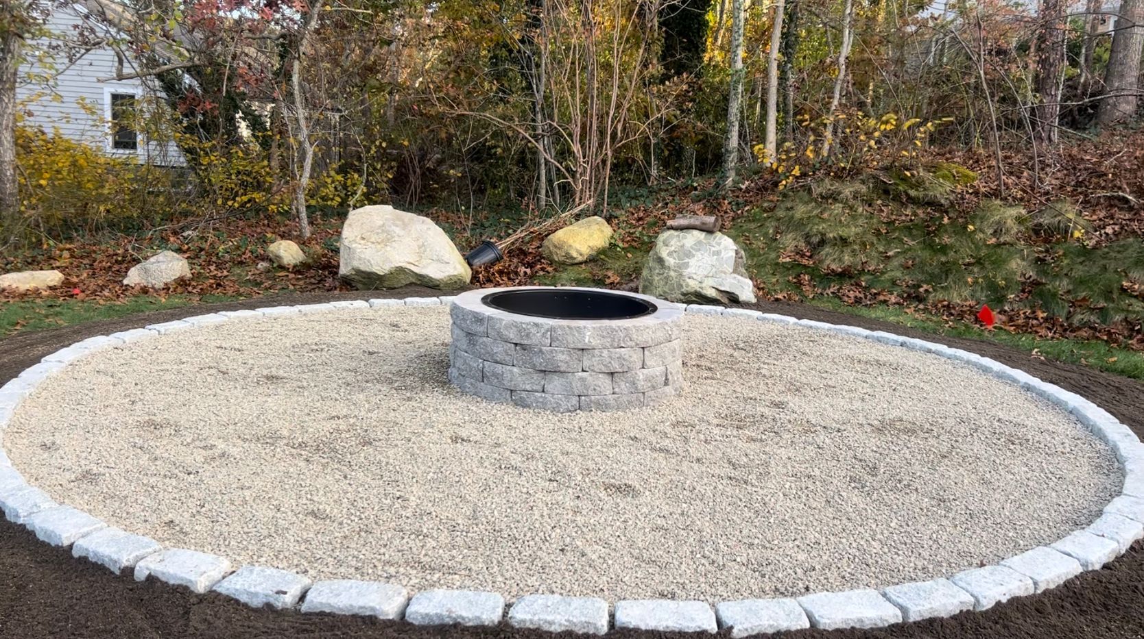 A fire pit surrounded by gravel and bricks in a circle