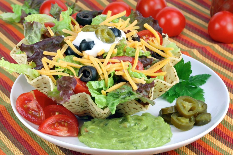 Taco salad in a crispy shell, with tomatoes, guacamole, jalapenos, olives, cheese, and sour cream.
