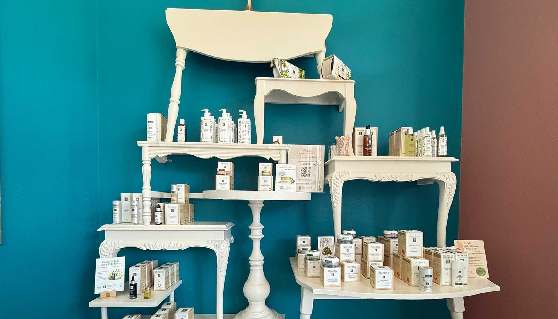 White tables displaying beauty products against teal and mauve walls.