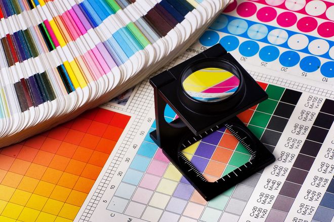 Color swatches, color charts, and a multicolor fan deck with stacked sample cards on a design table