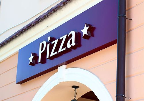 Pizza restaurant sign on a purple awning with white stars above an arched entrance