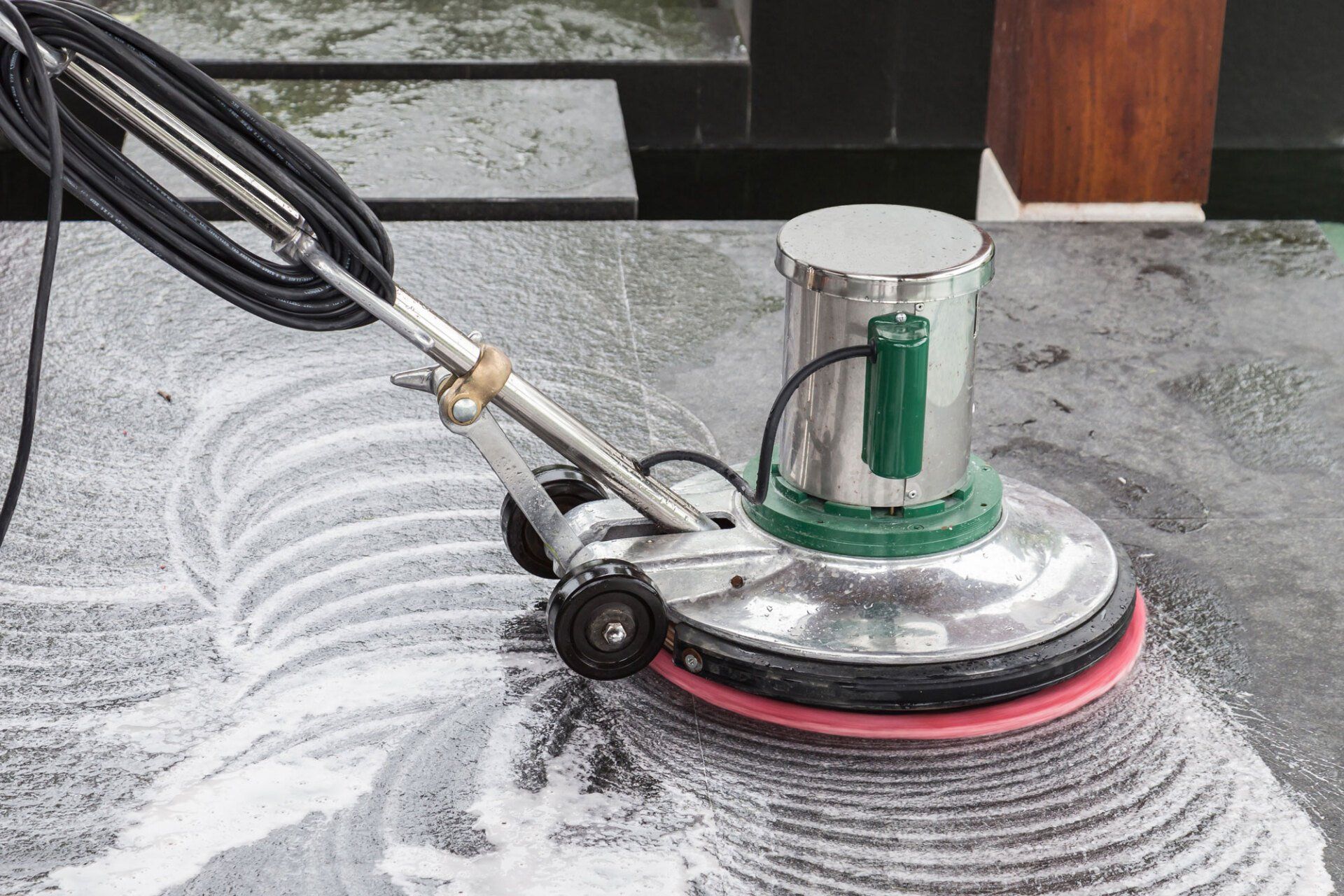 A machine is cleaning a marble floor with soap and water.