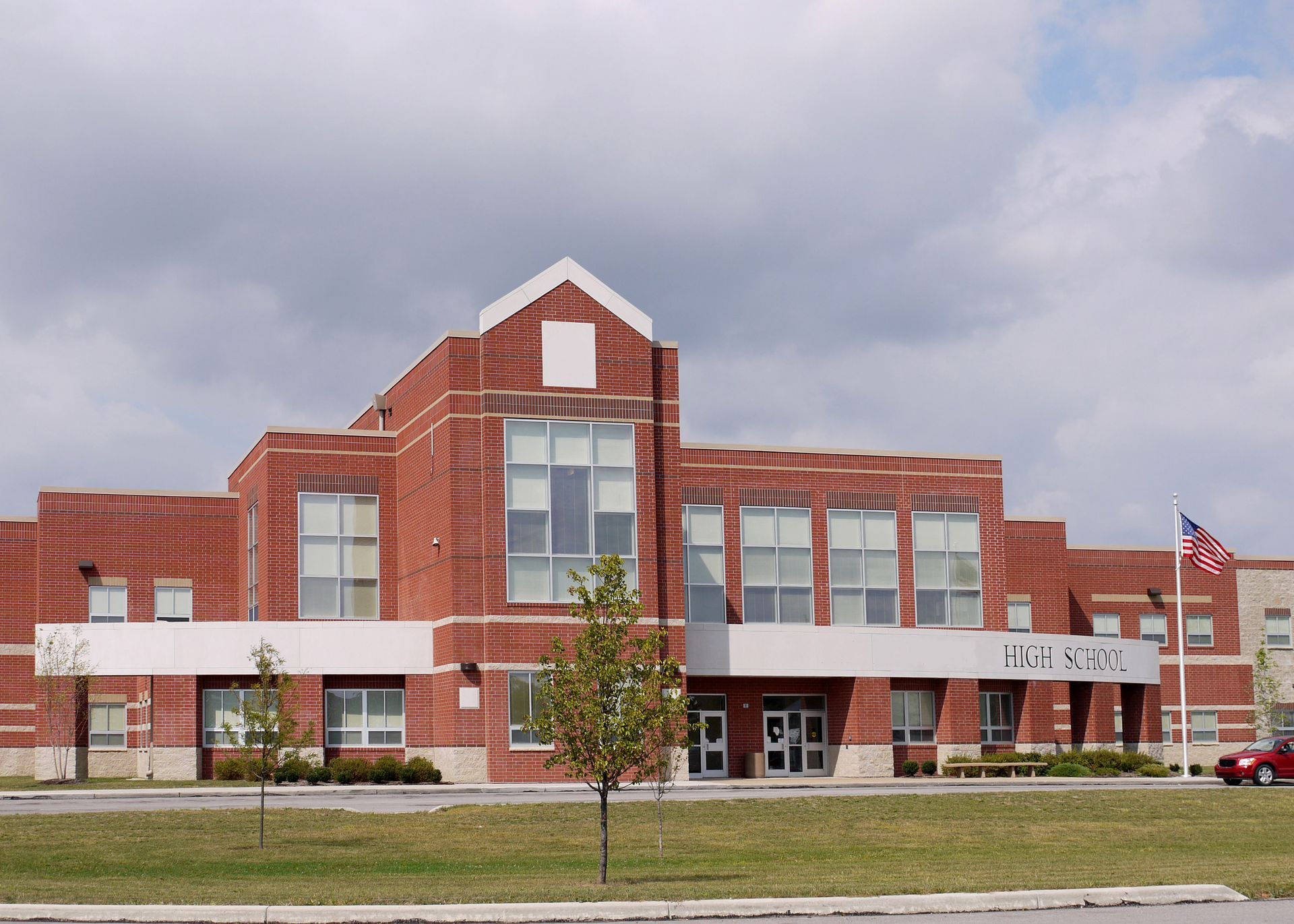 Red brick school building with a small American flag in front of a cloudy sky.